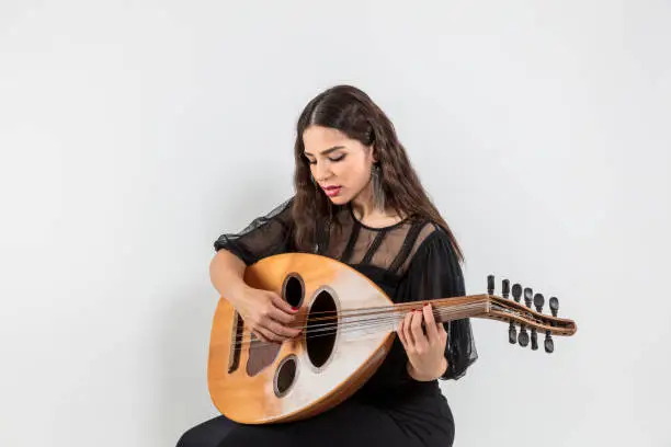 Photo of Oud playing women. Young woman playing lute string instrument