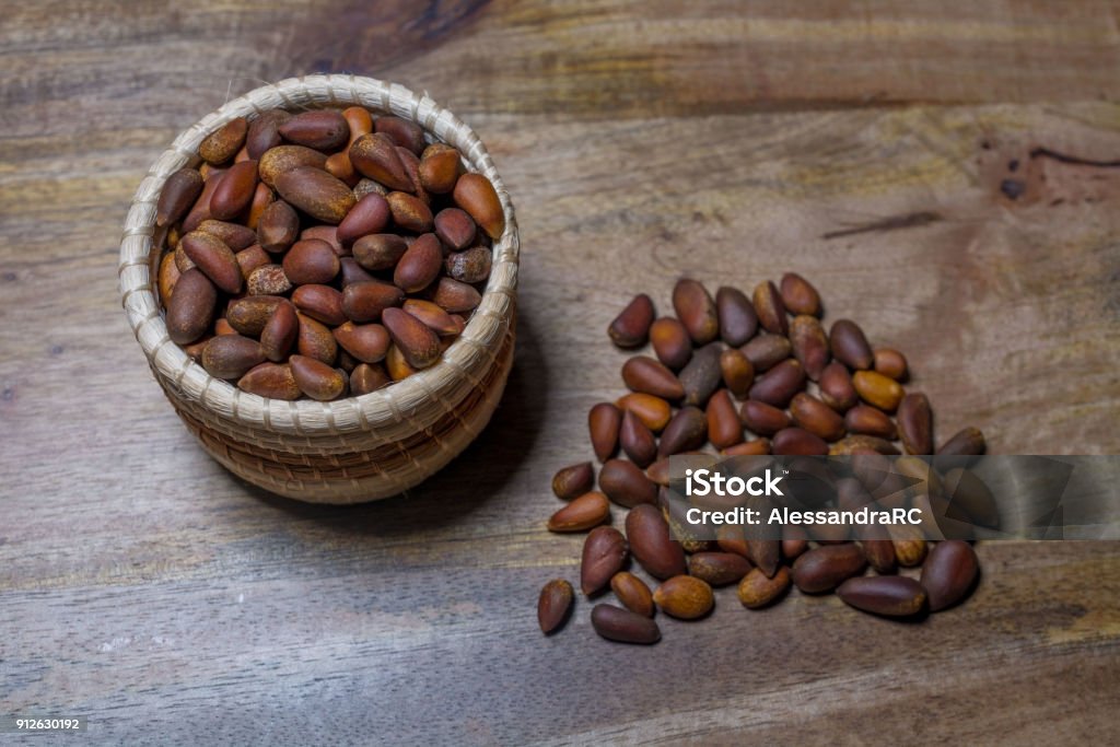Pine nuts A small basket with pine nuts deorated with pine nuts on aged wooden table Pine Nut Stock Photo