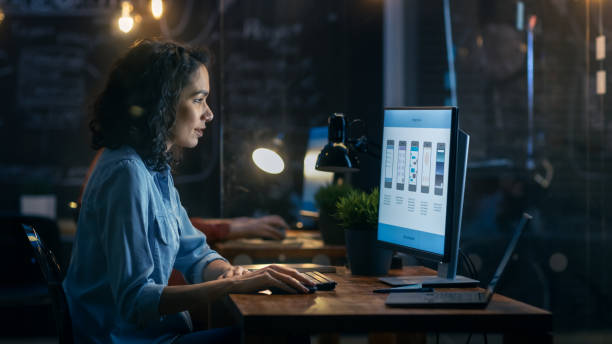 istock Beautiful Female Coder Works at Her Desktop on Her Peropnal Computer. Her Male Colleague Sits Next To Her. Evening Office Has Creative Lighting. 912636644