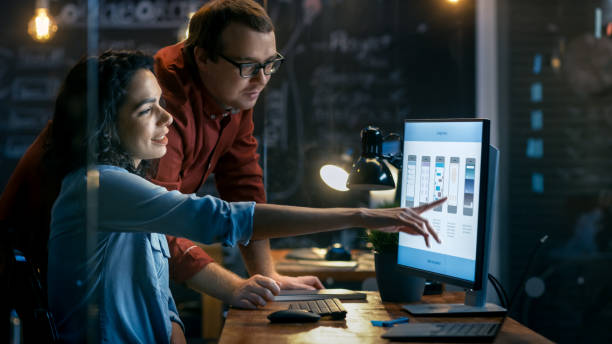 istock Beautiful Female Mobile Gaming Application Developer Talks With Her Male Colleague, They Discuss Creative Design. Stylishly Lit Office. 912636646