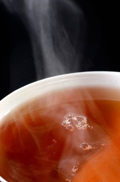 close-up of tea in cup filling tea cup isolated on black
