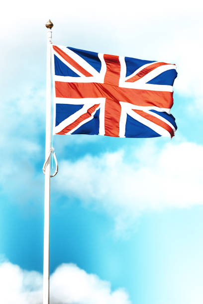 Bright Union Jack flag flying on white flag pole in blue sky
