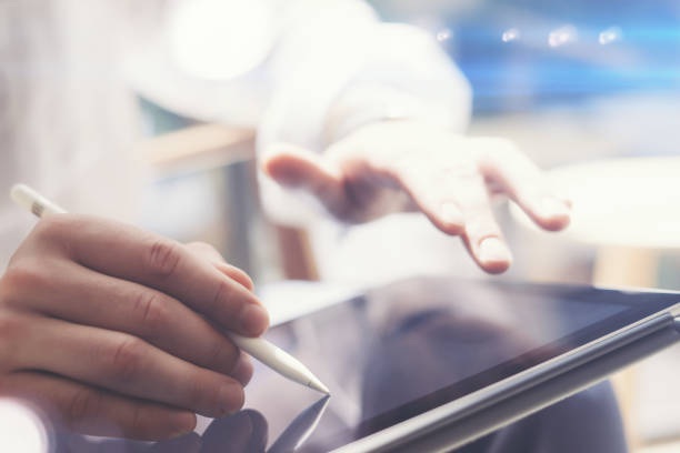 istock Closeup view of man holding digital tablet on hand and using electronic pen while working at sunny office.Pointing tablet screen.Blurred background.Horizontal. 912644946