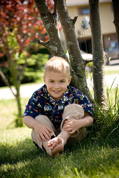 Young boy sits in grass stock photo