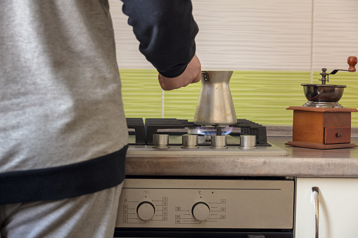 man from  back prepares coffee in  turkey on  stove in kitchen