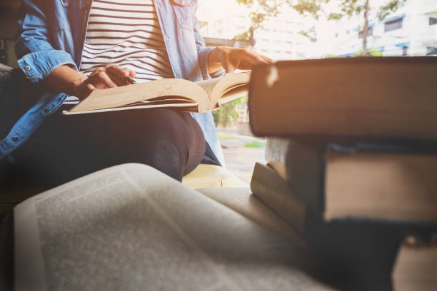 istock Midsection Of Woman Reading Book At University 912656562