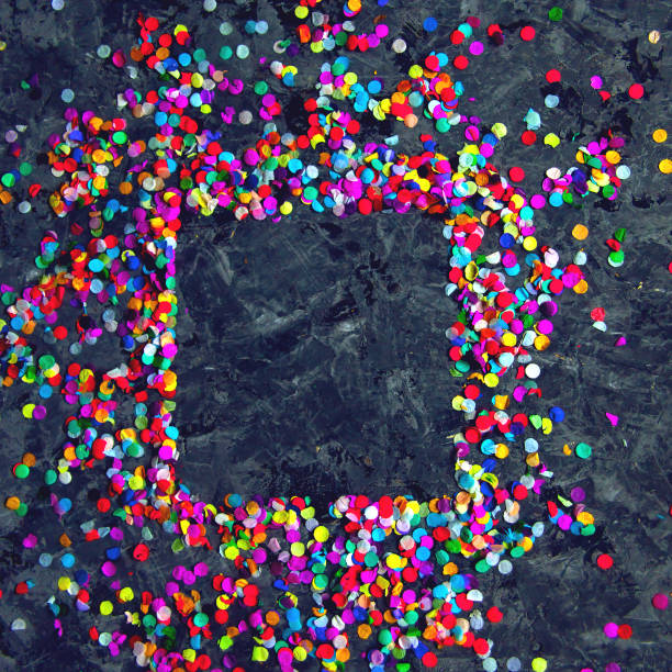 Champagne glasses with colored confetti sparkles over blue background. Flat lay, top view