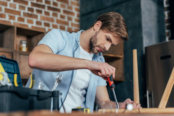 istock focused young man repairing stool with screwdriver 912658406