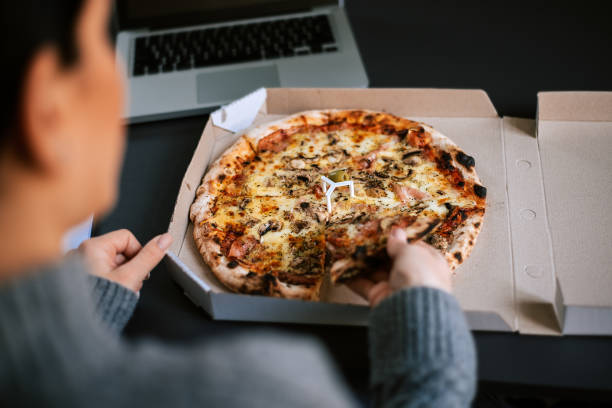 istock Woman eating pizza while working on laptop. 912663886