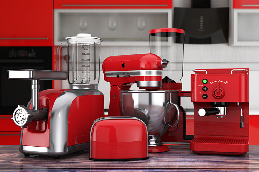 Kitchen Appliances Set. Red Blender, Toaster, Coffee Machine, Meat Ginder, Food Mixer and Coffee Grinder on a wooden table. 3d Rendering