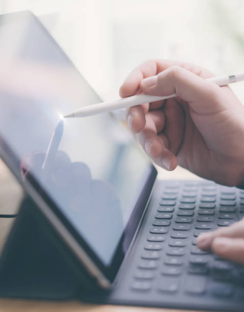istock Blogger using mobile touchpad for work.Closeup view of male hands using stylus pen for touching electronic tablet screen.Vertical, blurred background. 912671642