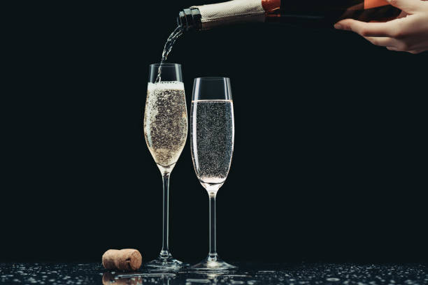 image recadrée de champagne battante femme de bouteille en verres sur fond noir - champagne pouring champagne flute glass photos et images de collection