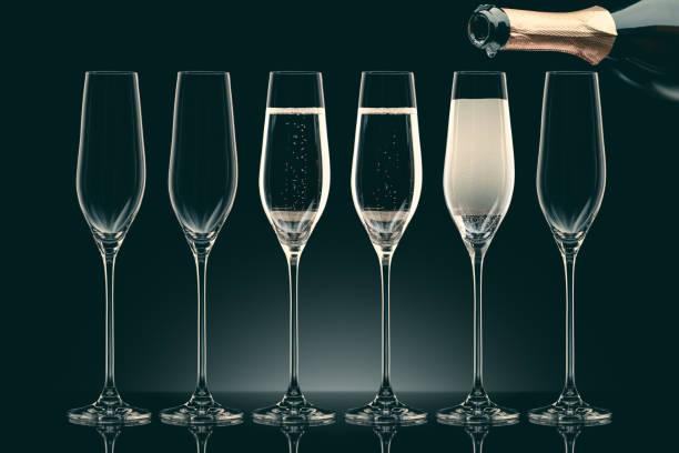 istock pouring champagne from bottle into six transparent glasses on black 912689922