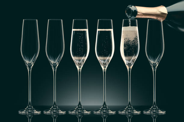 istock pouring champagne from bottle into six transparent glasses on black 912689960