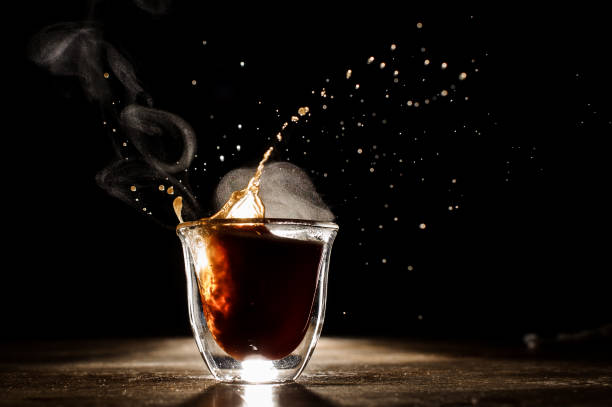 Hot and aromatic coffee spilling from glass cup