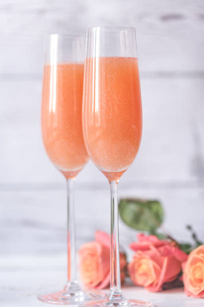 dois copos de cocktail bellini com buquê de rosas - champagne pink bubble valentines day - fotografias e filmes do acervo