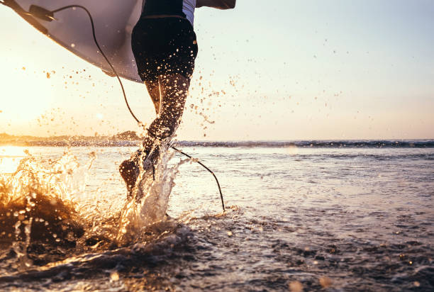 istock Closeup image water splashes from surfer's legs run in ocean with surfboard 912709052