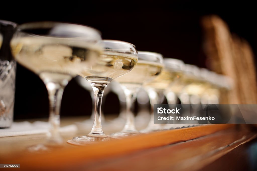 Set of elegant glasses with champagne arranged in line Set of elegant glasses with champagne arranged in straight line on the background of bar counter Alcohol - Drink Stock Photo