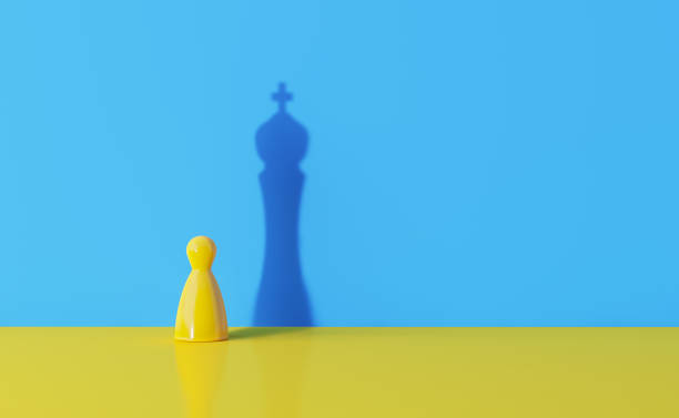желтая шахматная пешка, бросают тень короля на синий фон - photography chance aspirations yellow стоковые фото и изображения