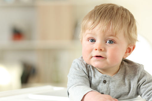 Front view portrait of a relaxed baby looking at you at home