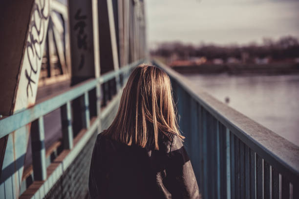 A girl walking across the bridge A girl wearing black leather jacket walking across the freight bridge over river Danube teenage girls dusk city urban scene stock pictures, royalty-free photos & images