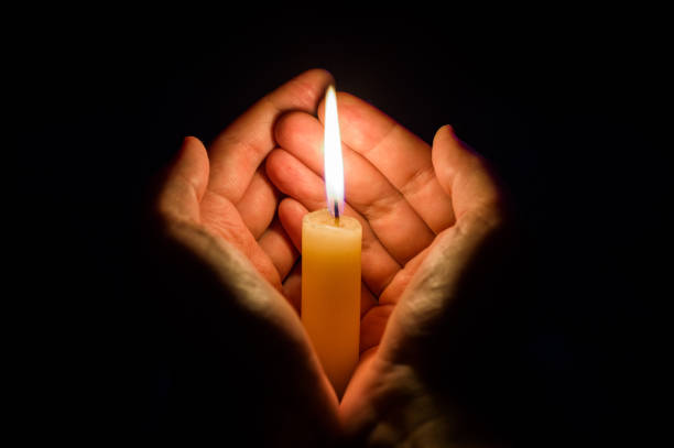 istock hands holding a burning candle in dark like a heart 912738018