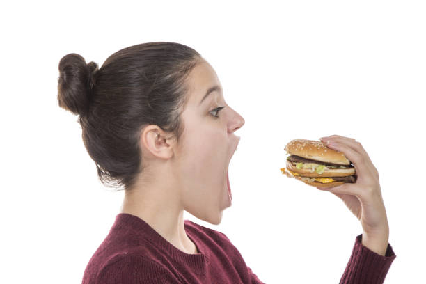 istock Adolescent girl eating a hamburger 912744924