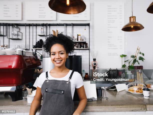 Young Smiling Barista Wearing Apron Standing At Cafe Counter Stock Photo - Download Image Now