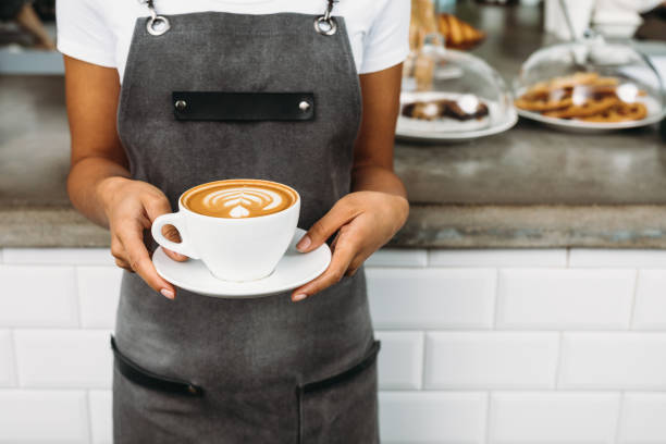 istock Unrecognizable waitress holding a cup of latte with rosetta in cafe 912751470