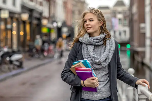 Photo of Beautiful female university student studying outdoors in delft city centre