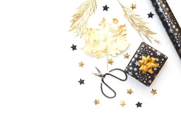 Photo of Flat Lay with Gift box and Wrapping Paper in Gold and Black tones. Isolated on white. Party preparation