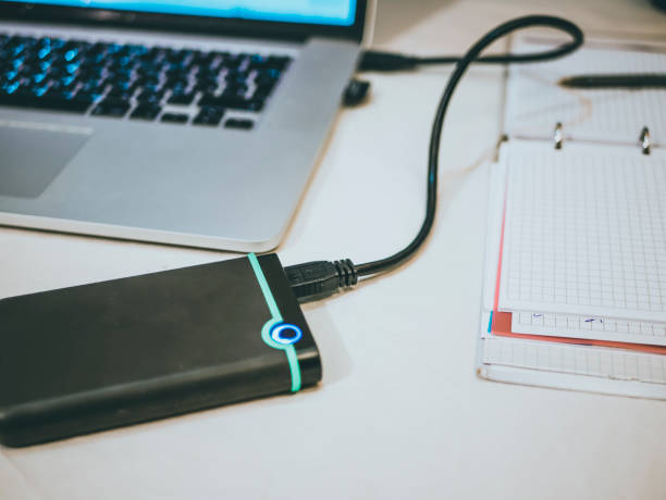 istock external hdd (ssd) connected to the laptop on the white surface