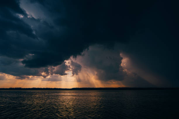 istock dramatic dark sky with rain clouds and sun over river in evening summer sunset 912776112