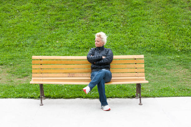 istock Mature woman sitting on park bench. 912780072