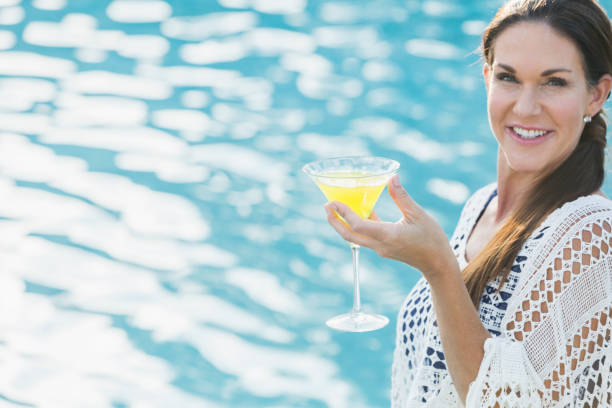 istock Mature woman with martini by swimming pool 912782648