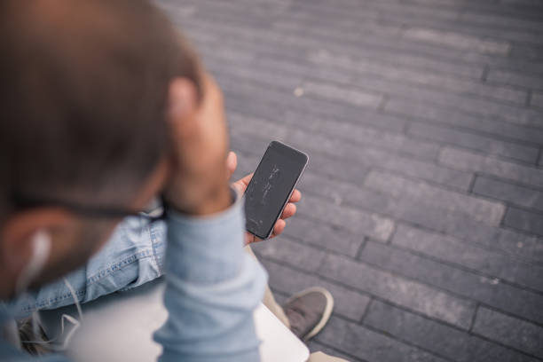 Displeased man with broken smartphone Displeased man holding smartphone with broken screen man hand down stock pictures, royalty-free photos & images