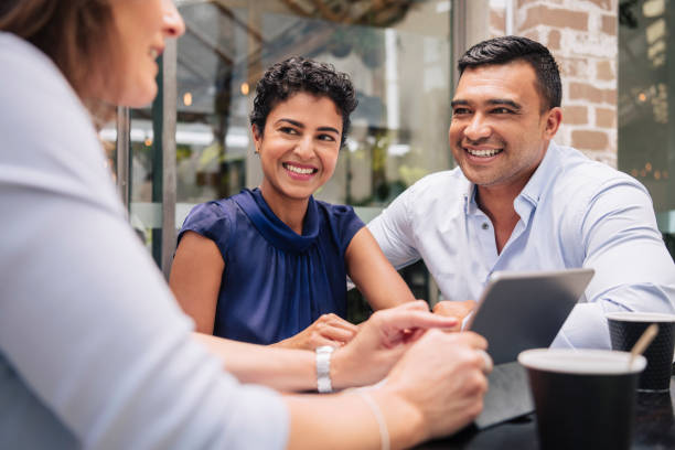 szczęśliwa para otrzymuje dobre wieści od profesjonalnej bizneswoman - business asian ethnicity multi ethnic group business meeting zdjęcia i obrazy z banku zdjęć