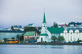 View of Tjornin - small lake in central Reykjavik, of Iceland with Frikirkjan Church, fountain in the middle and people walking around