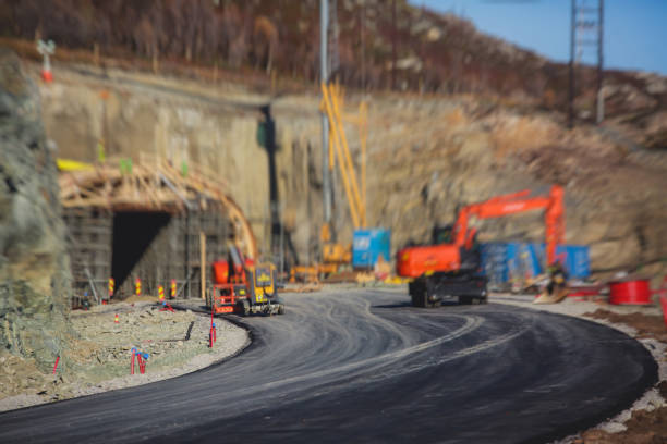 Construction site, process of new road construction with heavy vehicle at building work, heavy excavator and bulldozer unloading road metal during road work\
