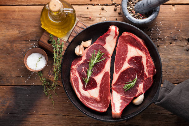 istock Two fresh raw marble meat, black Angus ribeye steak with spices in iron pan on a old rustic table. Raw beef on a wooden background. Top view with copy space 912815262