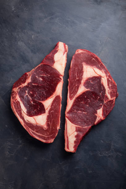 Raw fresh marbled meat Steak Ribeye Black Angus on black marble background. Beef with spices on a dark stone table. Top view