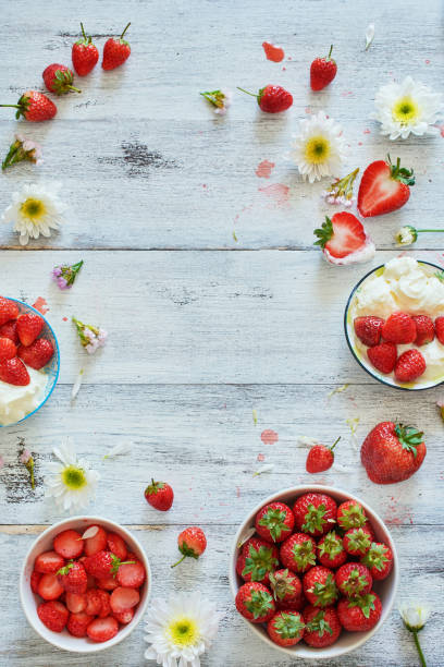 istock Fresh strawberry with whipped cream food frame decorated with flowers over white table. Copy space. 912819650