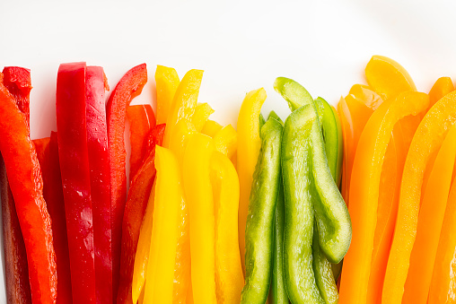 Red, Orange, Green and Yellow Bell Peppers, Sliced, on a white background