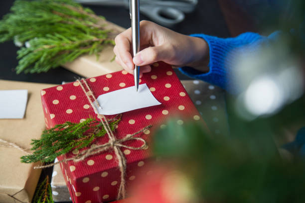 Write Christmas greetings in a card and giving present for festival stock photo