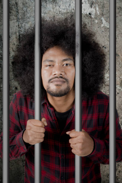 istock Male drunkard standing in the jail 912823414