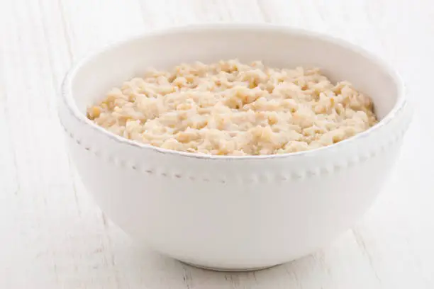 Delicious nutritious and healthy fresh old fashioned oatmeal on antique wood table