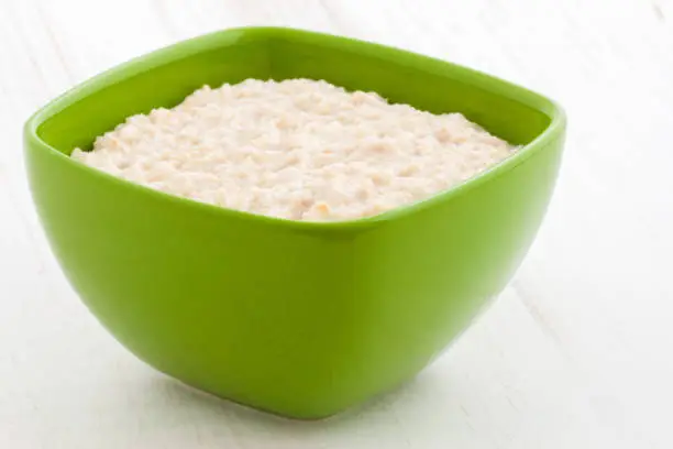 Delicious nutritious and healthy fresh old fashioned oatmeal on antique wood table