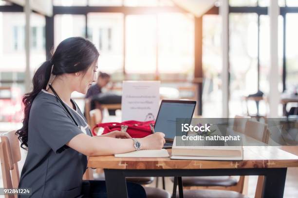 Concentrated Doctor Or Nurse Working On Line With A Laptop Sitting In A Desk In A Consultation Stock Photo - Download Image Now