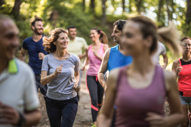 szczęśliwa dojrzała para rozmawia podczas biegu maratonu przez las. - jogging off track running women running zdjęcia i obrazy z banku zdjęć