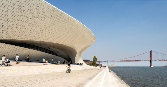 People enjoying the riverside promenade in front of the manta ray shaped MAAT (Museum of Art, Architecture and Technology) in Lisbon, Portugal